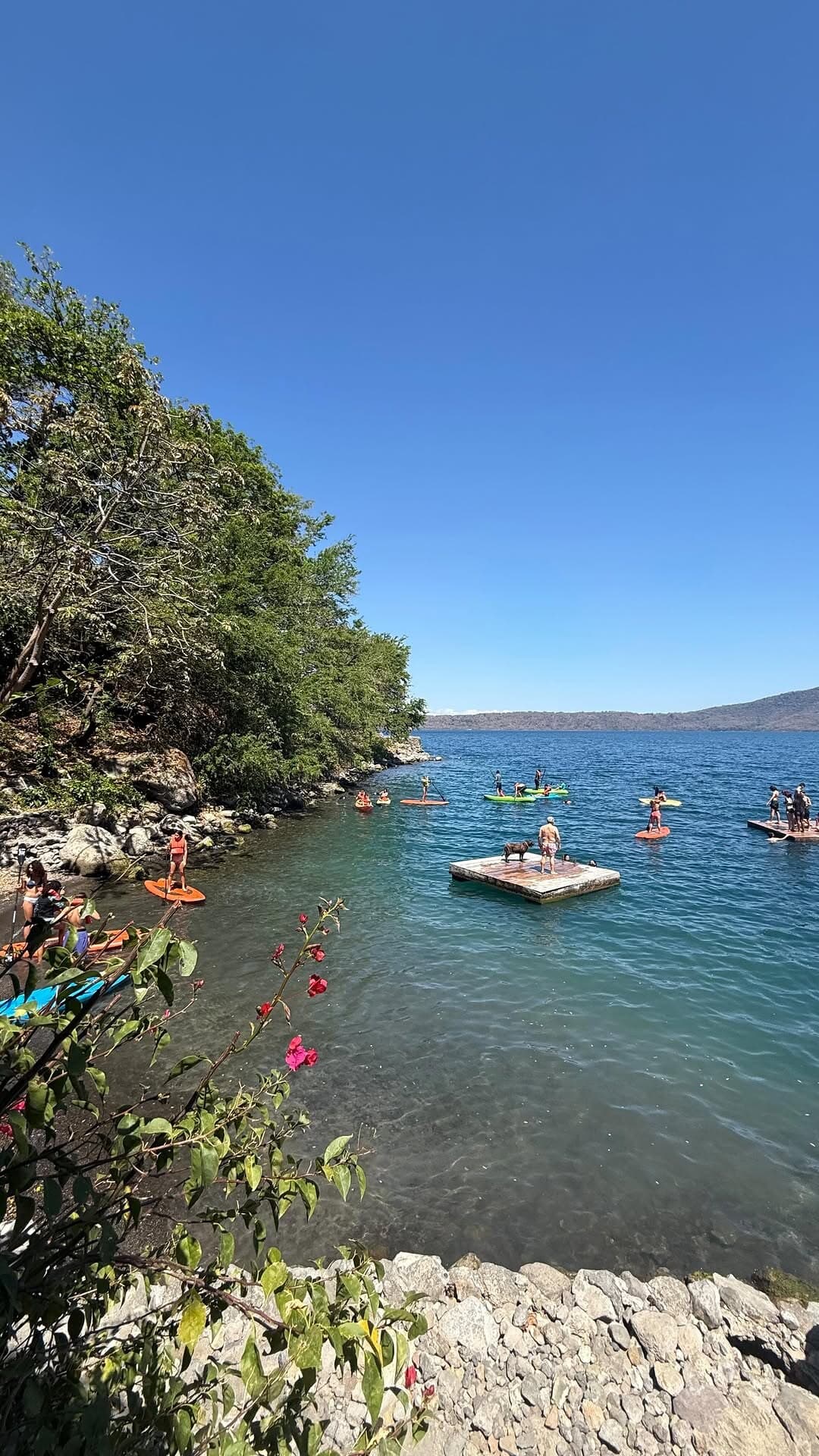 Journey students paddle-boarding and kayaking on a calm blue lagoon, forested shoreline behind