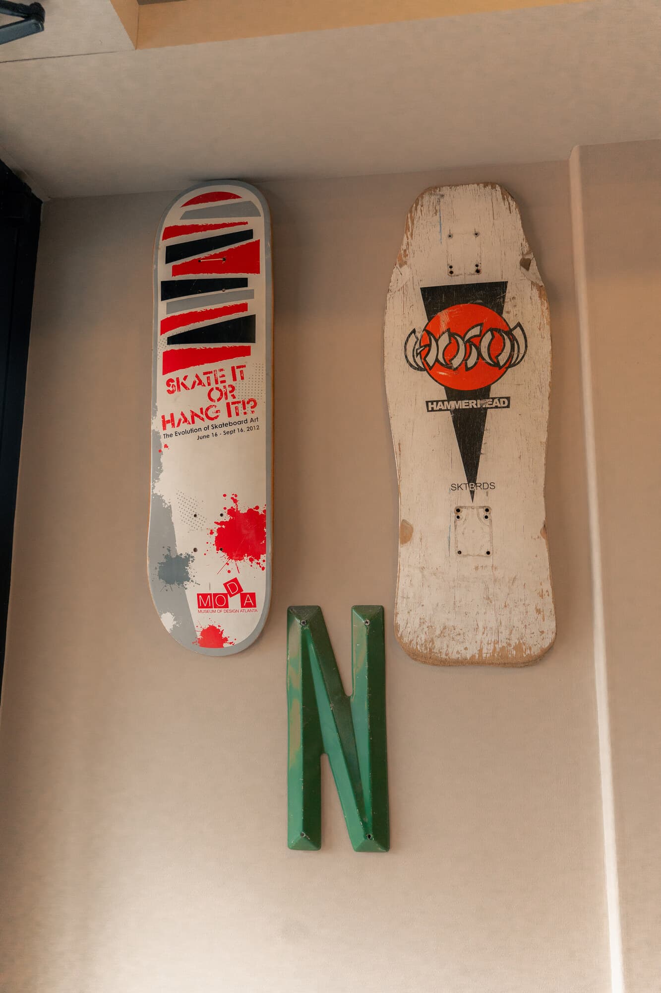 Student skateboard art exhibit at Tamarindo — boards mounted on wall under 'SKATE IT OR HANG IT?' signage