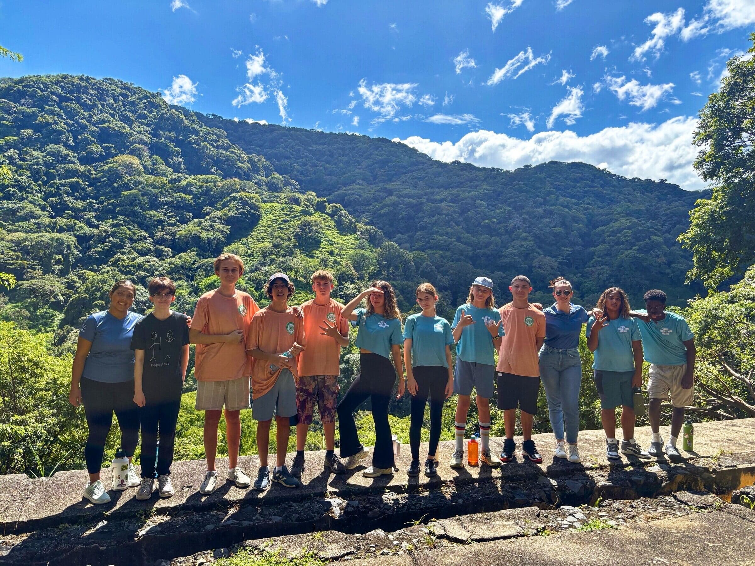 Journey MUN team on a stone overlook with rainforest mountains behind