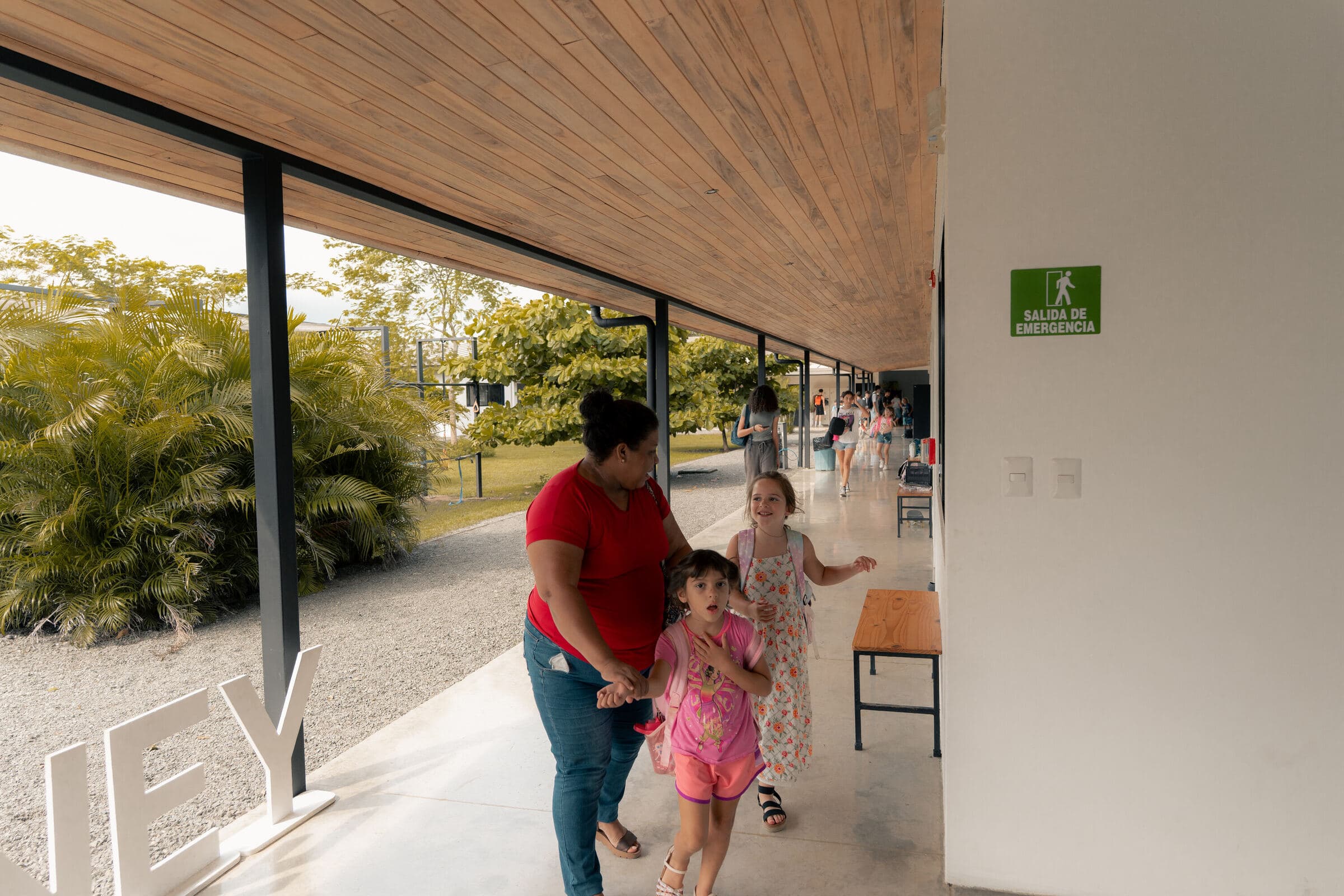 Family walking through Tamarindo campus covered walkway with wood ceiling