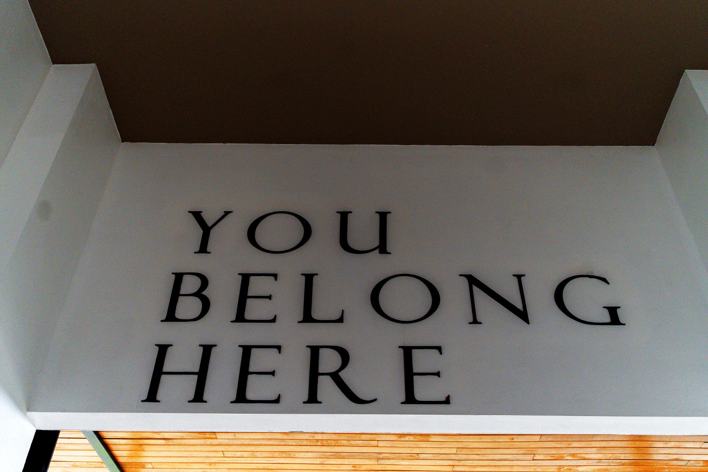 'YOU BELONG HERE' wall mural at the Tamarindo campus, dark architectural beam at top